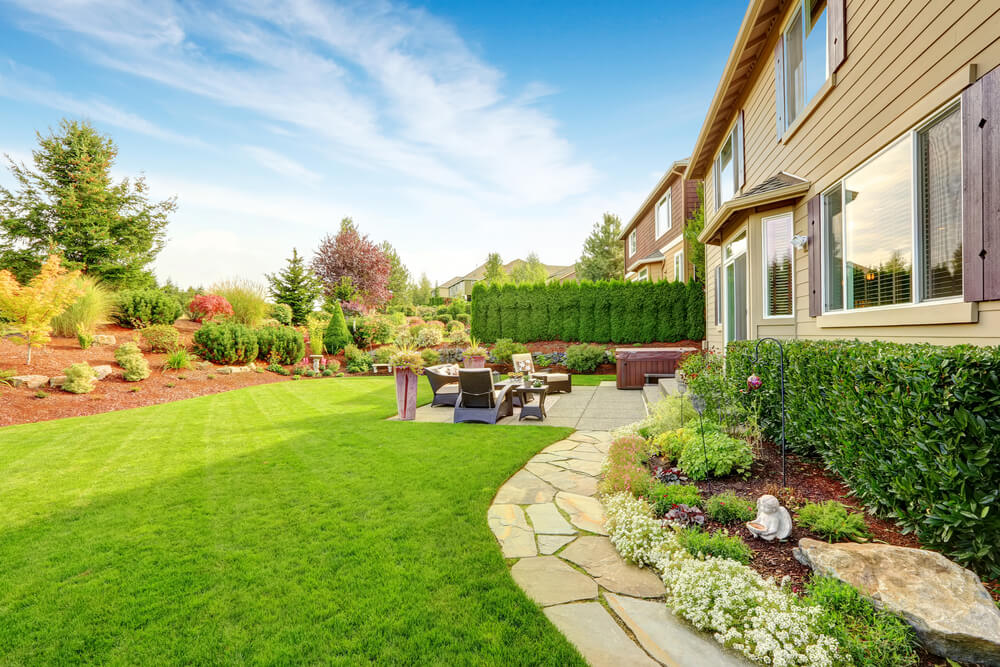 a large backyard with rich green grass and a stone path leading to an outdoor setting that's had good Garden Landscaping